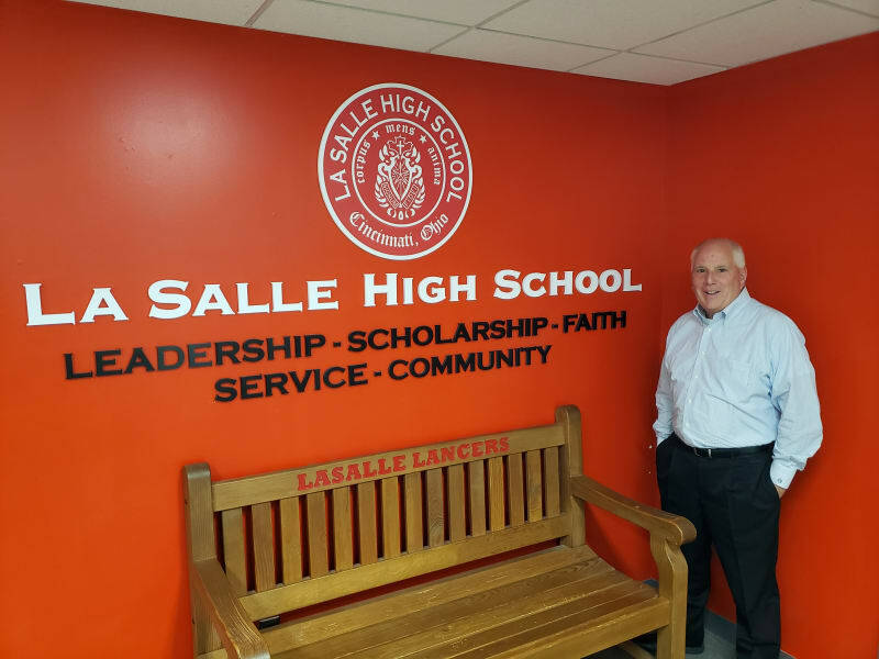 Bob Dorsey standing in front of LaSalle's logo on a wall and next to a bench